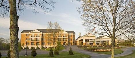 Een hotel met meerdere verdiepingen, een centrale binnenplaats, een overdekt terras en een aangelegde oprijlaan.