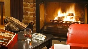 A cozy room with a fireplace, a table with a glass of wine, and a red chair. - The Resort at Glade Springs (Daniels)