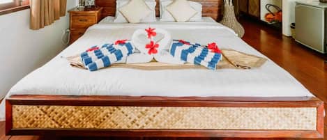A neatly made bed with a woven headboard, a bedside table, and a decorative vase.