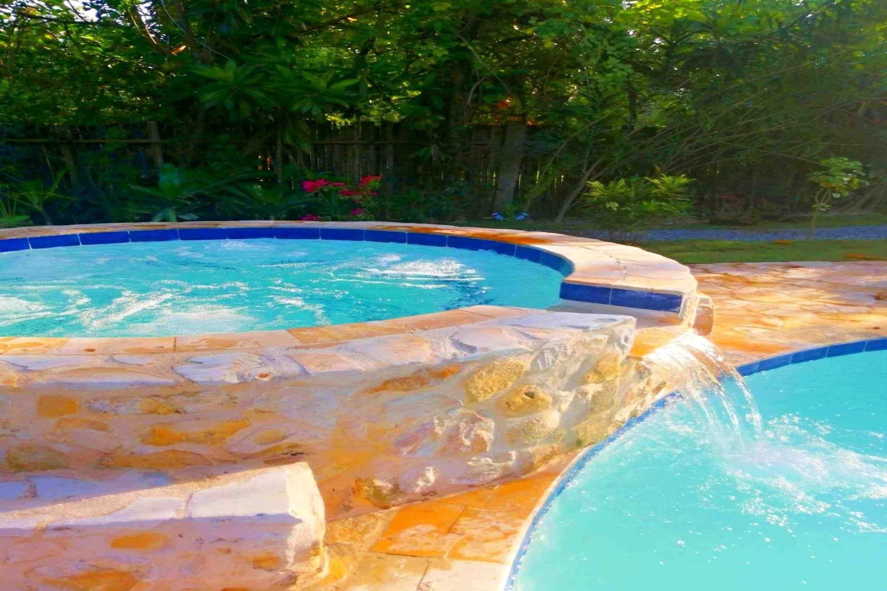 A swimming pool with a stone border and a waterfall feature.