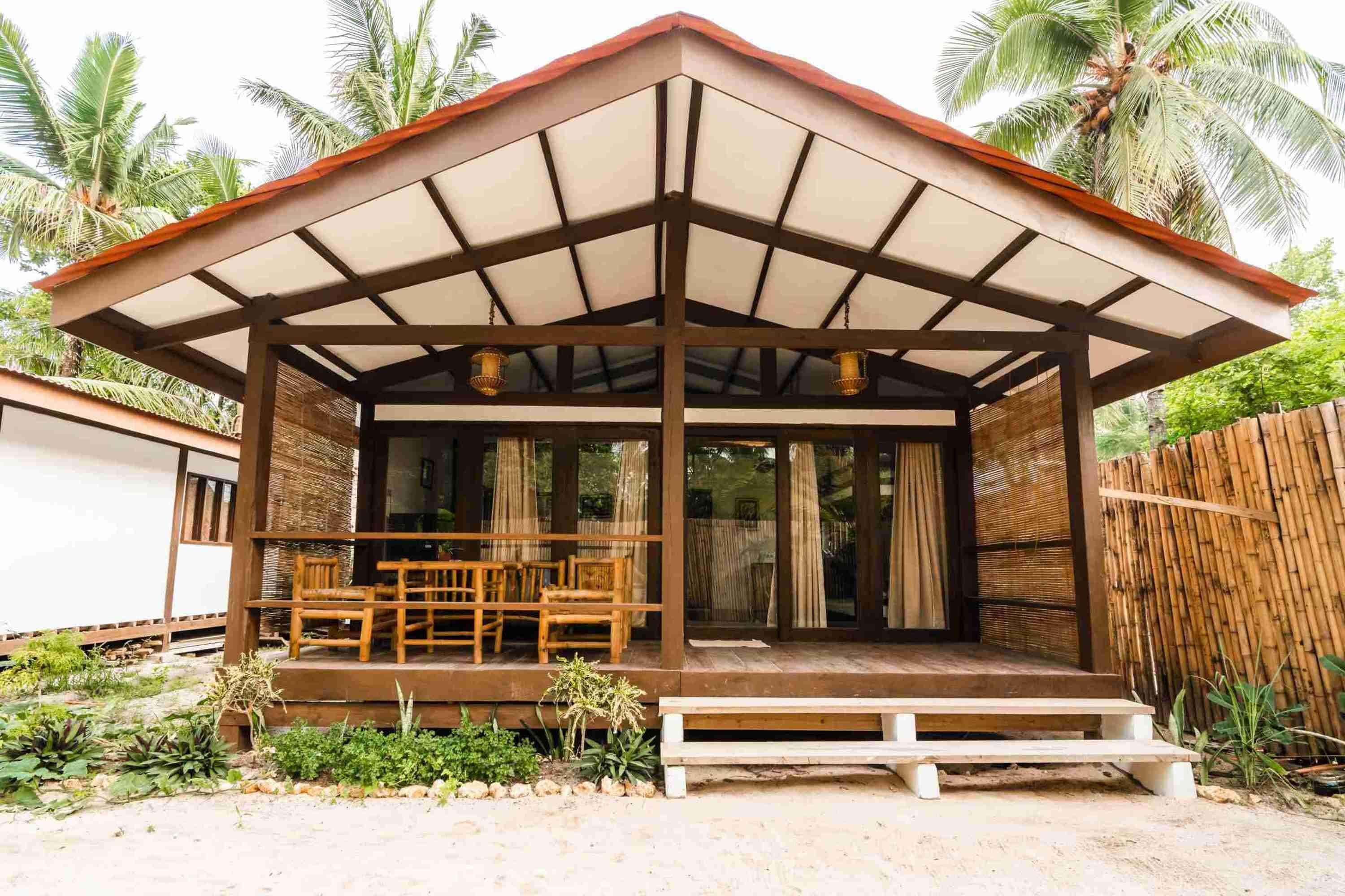 A covered outdoor seating area with wooden furniture and a view of the surrounding landscape.