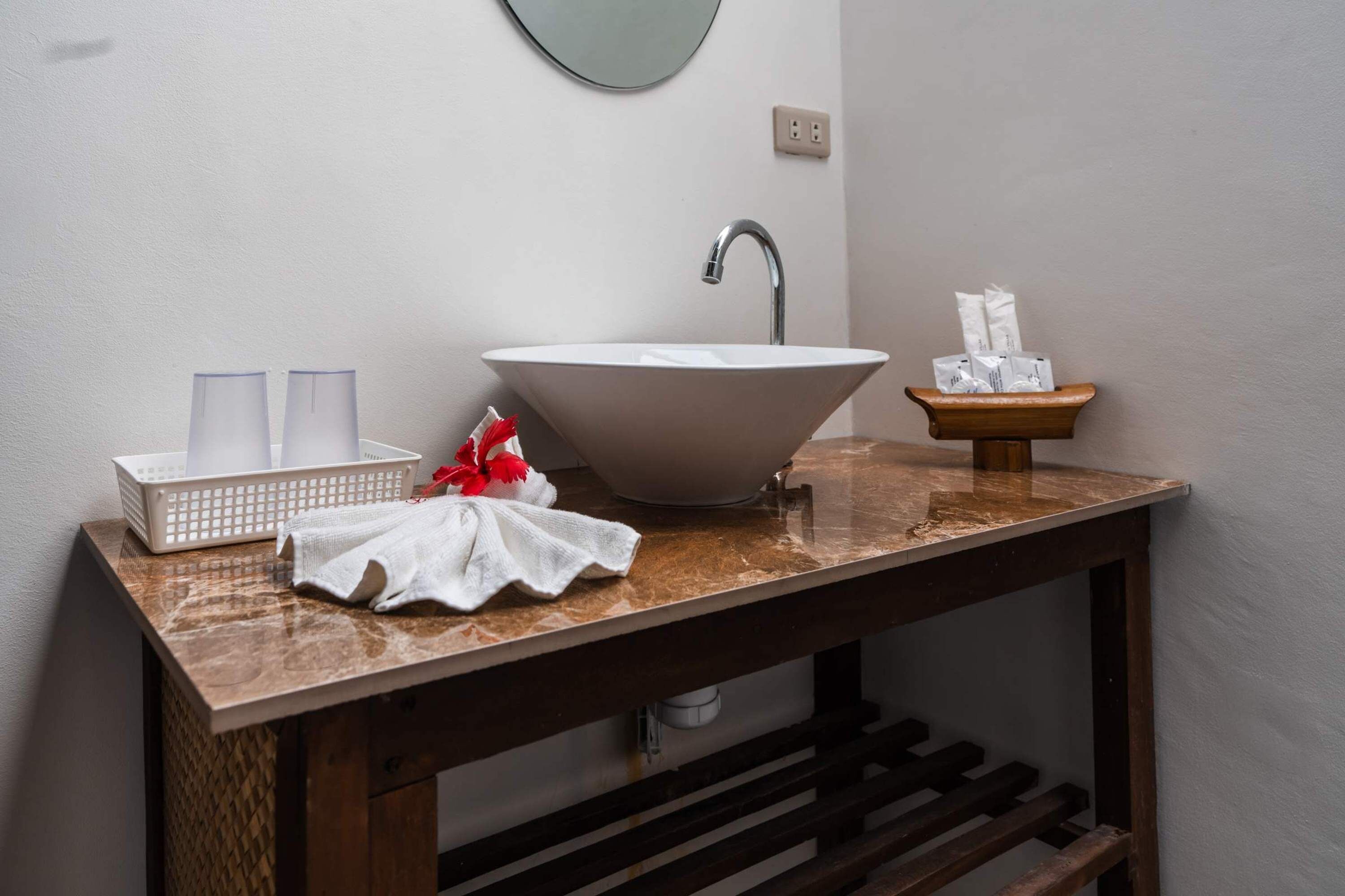 A bathroom with a white sink, a mirror, a towel, and a tissue holder.