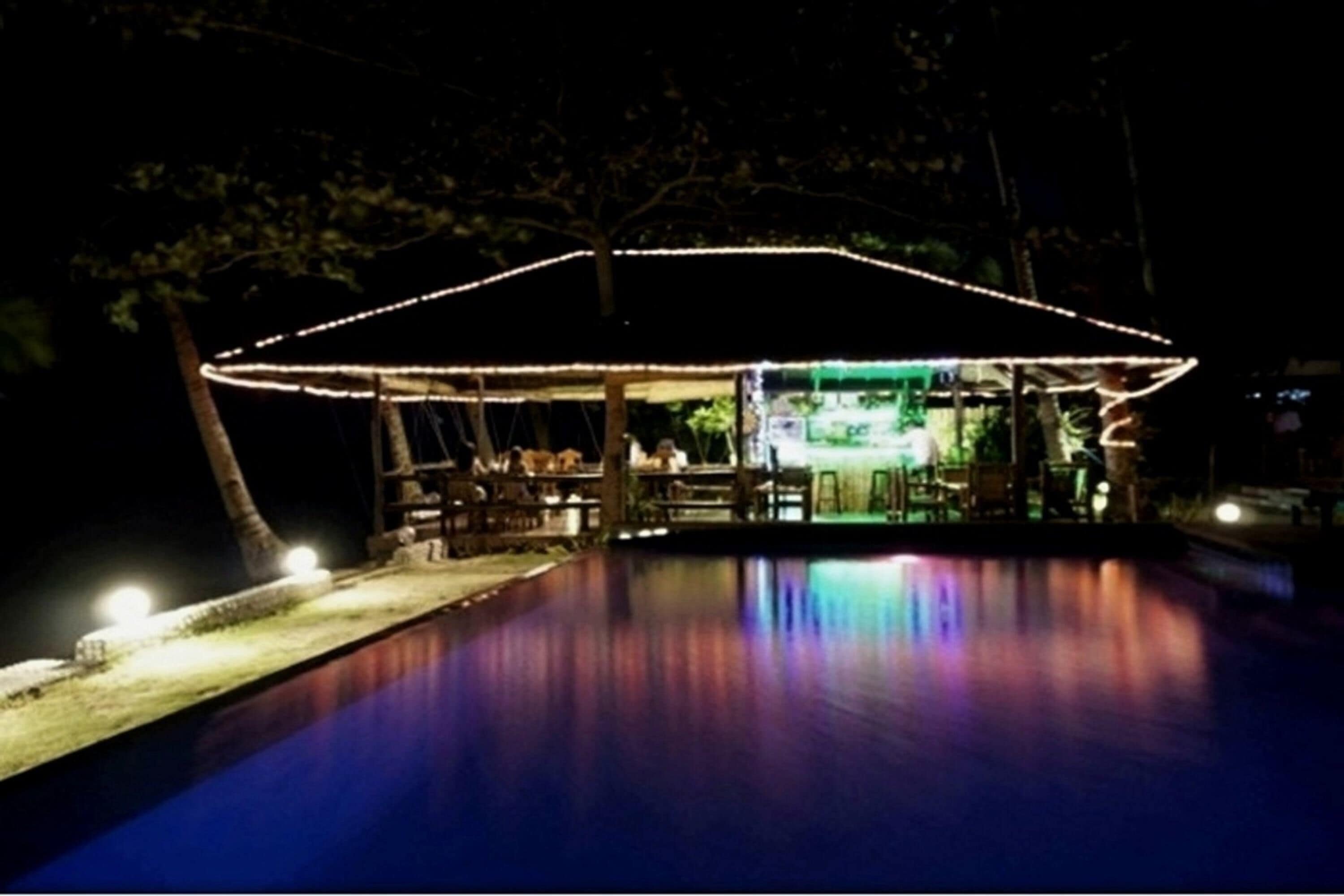 An outdoor pool area with a covered seating area and a bar.