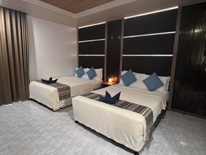A hotel room with two beds, a nightstand, and a wall-mounted light fixture. - Panglao Pearl Premier White Sand Resort (Panglao)