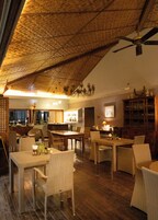 A spacious living area with a high ceiling, wooden flooring, and wicker furniture.