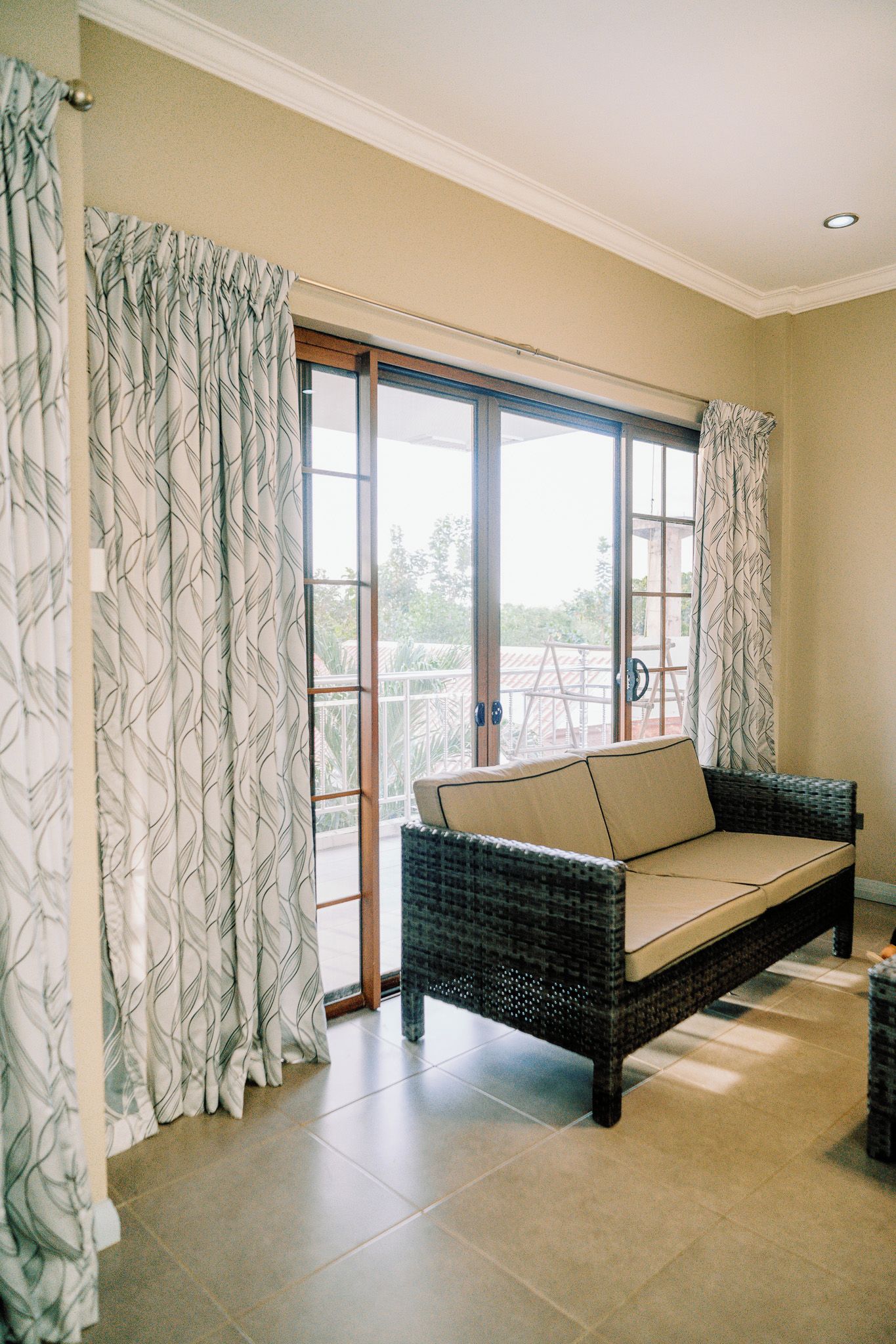 A room with a wicker sofa, a sliding glass door, and a view of the outdoors.