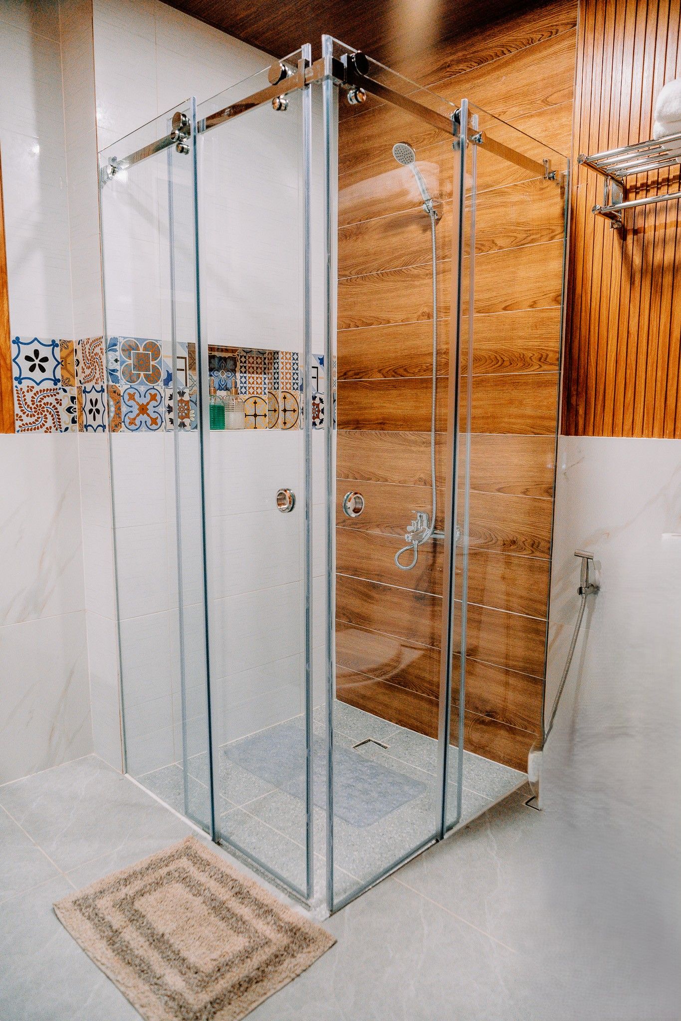 A glass-enclosed shower with a wooden panel wall and a tiled backsplash.