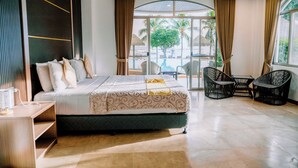 Une chambre d’hôtel avec un lit, une petite table, une chaise et une vue sur la plage.