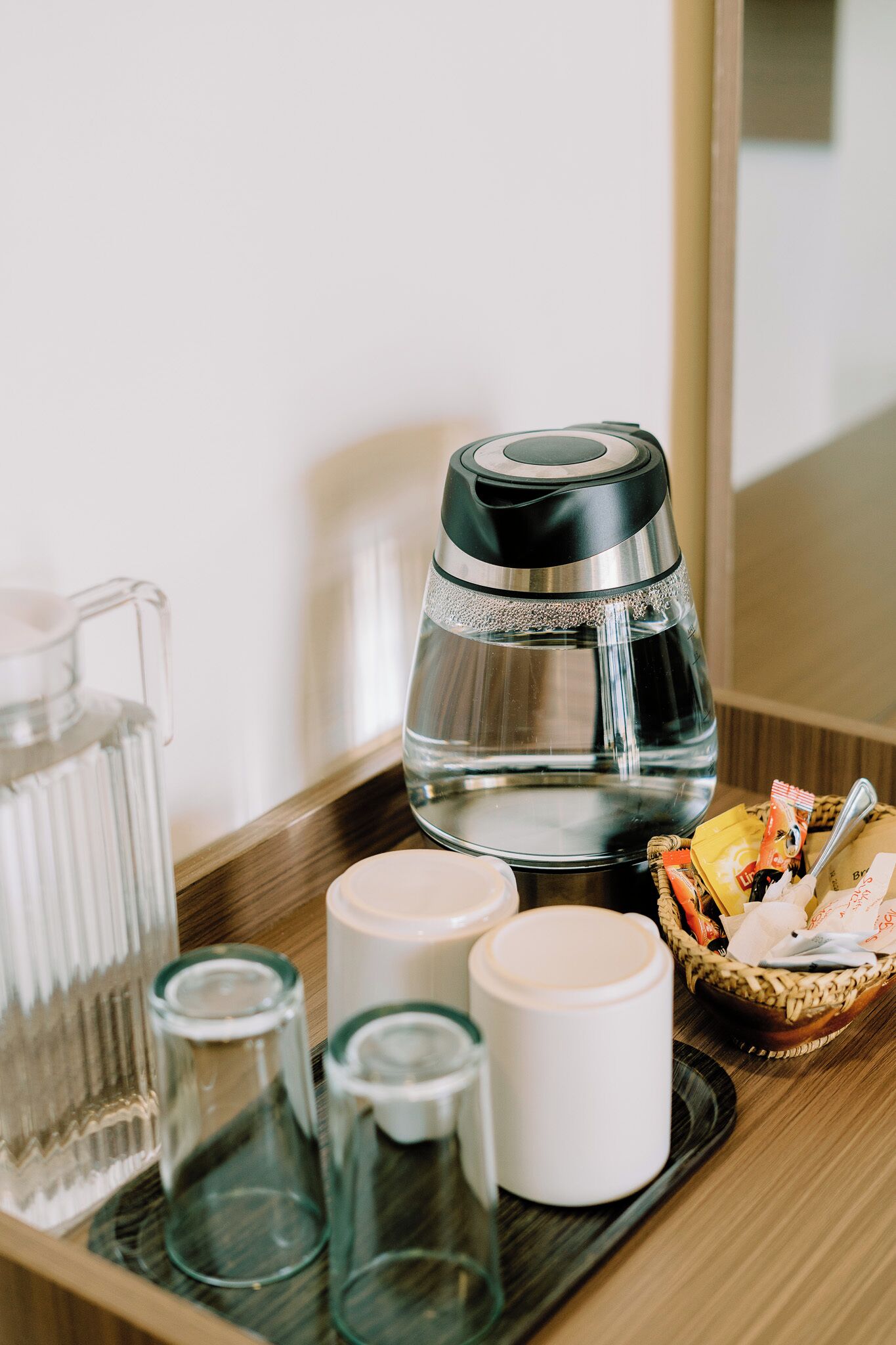 A tray with a coffee maker, a pitcher, and two cups on a wooden surface.