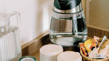 A tray with a coffee maker, a pitcher, and two cups on a wooden surface.