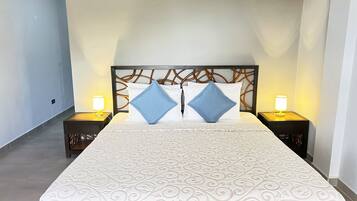 Una cama bien hecha con una colcha estampada, dos almohadas y dos lámparas de noche.