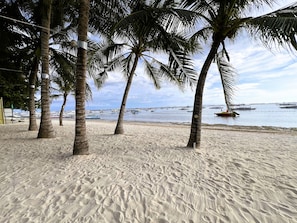 A sandy beach with palm trees and boats in the water. - Panglao Pearl Premier White Sand Resort (Panglao)