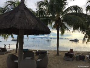 Di pantai, pasir putih, kursi berjemur, dan handuk pantai