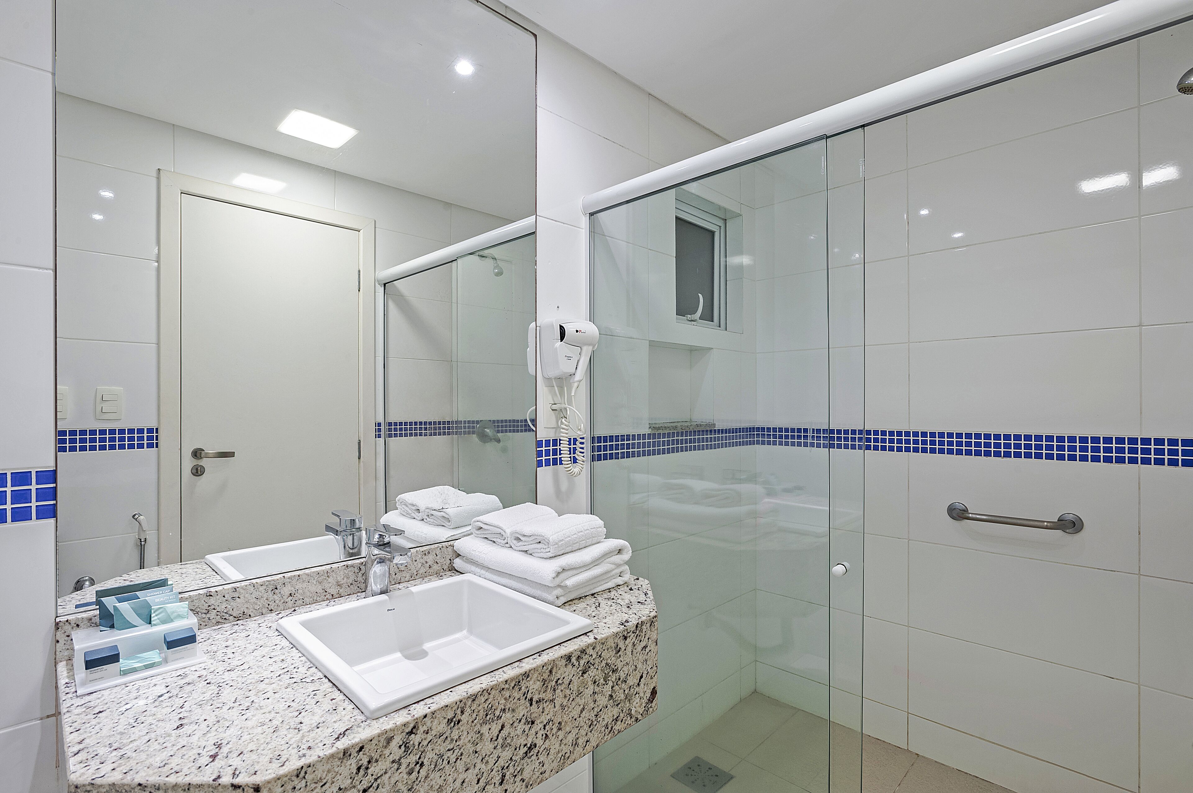 A modern bathroom with a glass shower enclosure, a sink with a marble countertop, and a mirror.