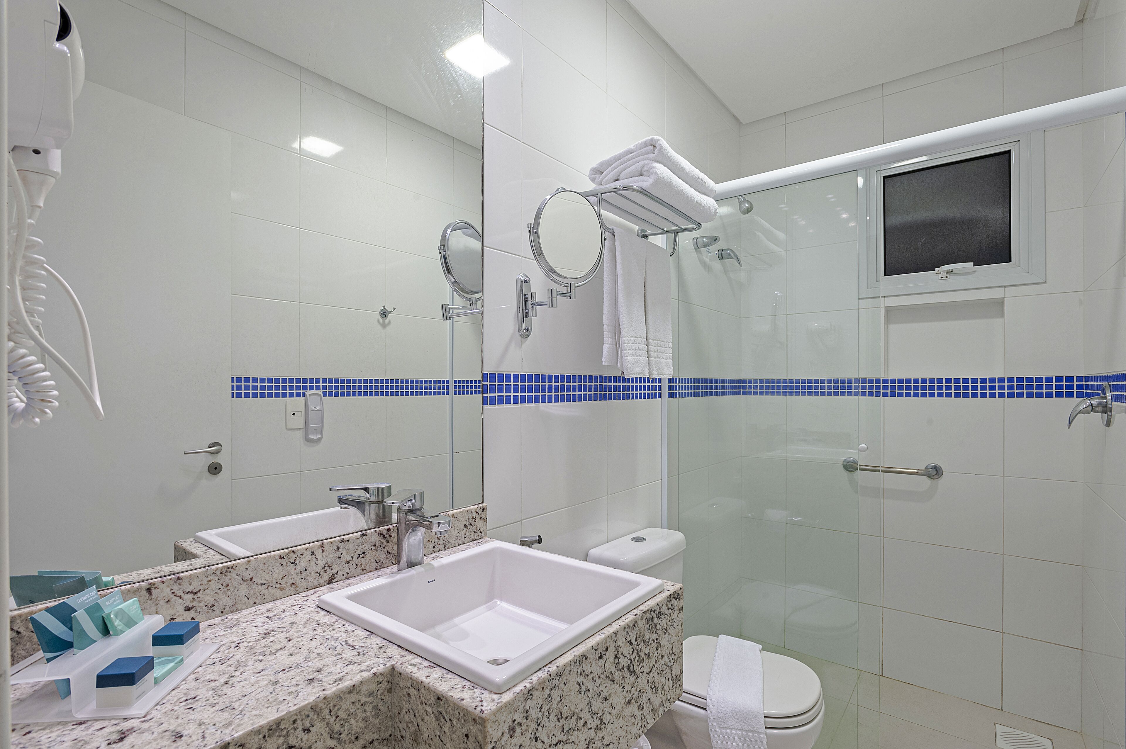A modern bathroom with two sinks, a glass shower enclosure, and a toilet.