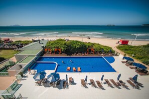 A pool area with lounge chairs and umbrellas, overlooking a beach and ocean. - SLAVIERO  Ingleses Convention (Florianópolis)