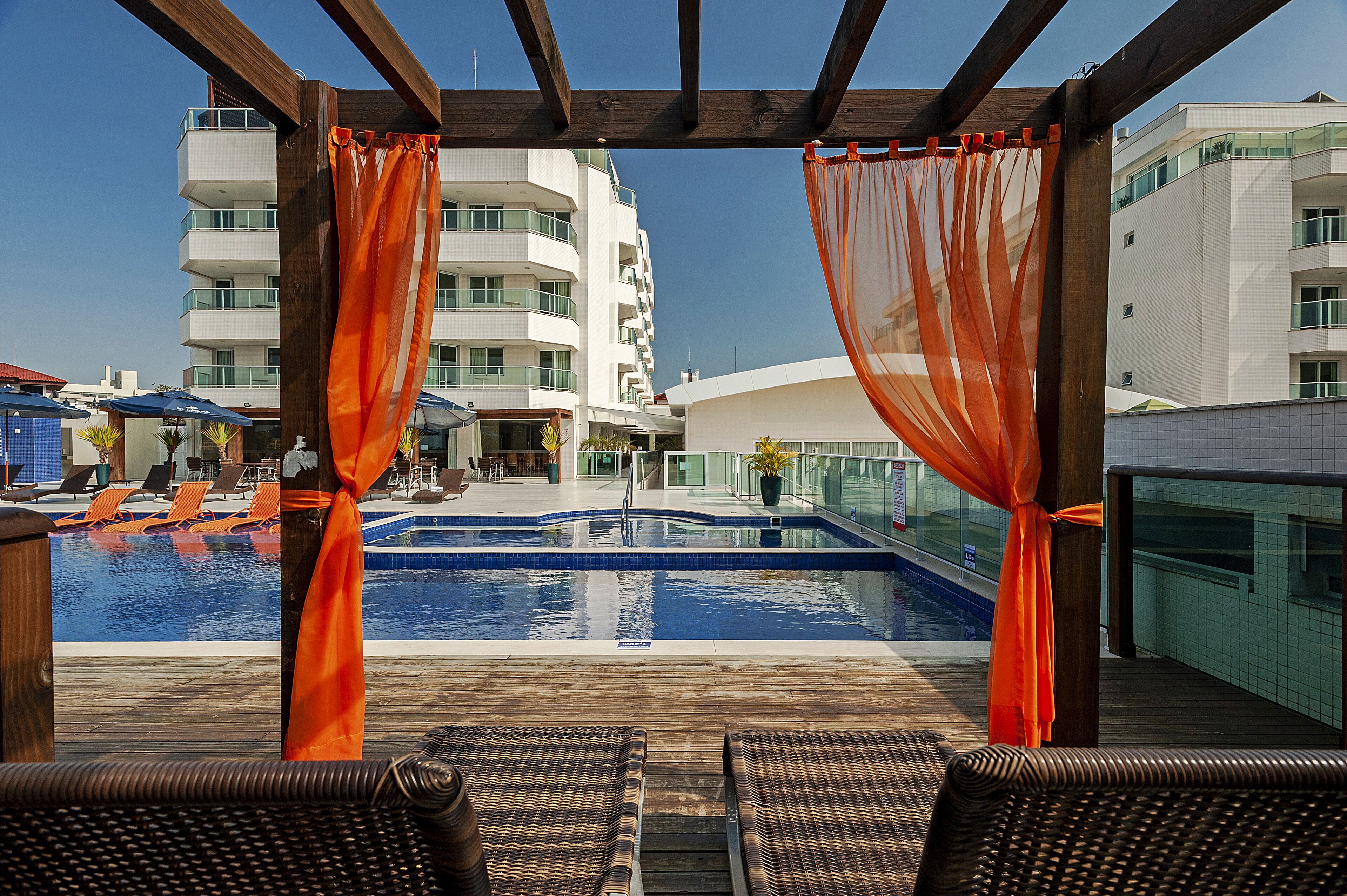 A poolside area with lounge chairs, a swimming pool, and a building in the background.