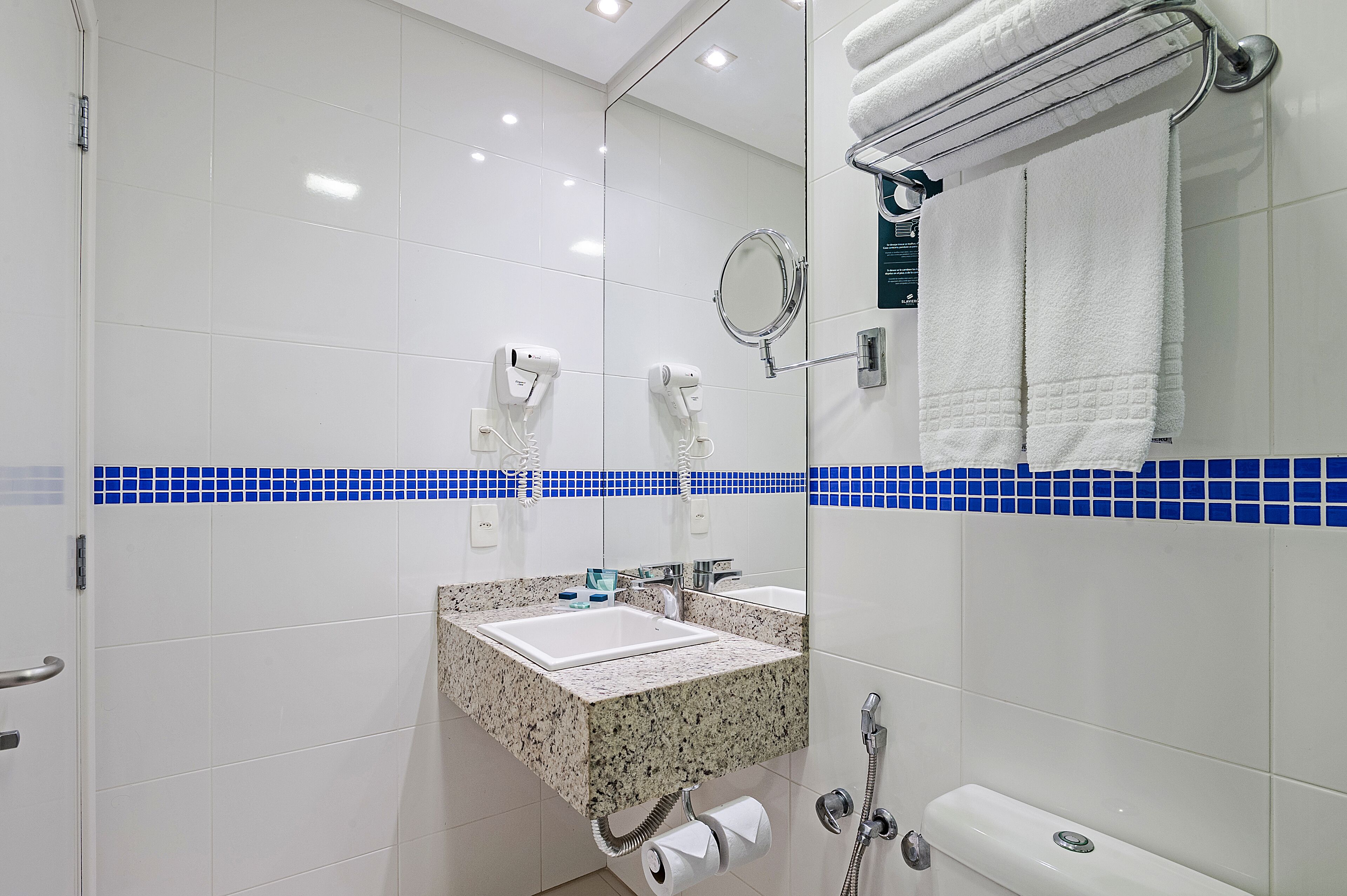 Een moderne badkamer met een witte wastafel, een spiegel, een handdoekhouder en een douche.