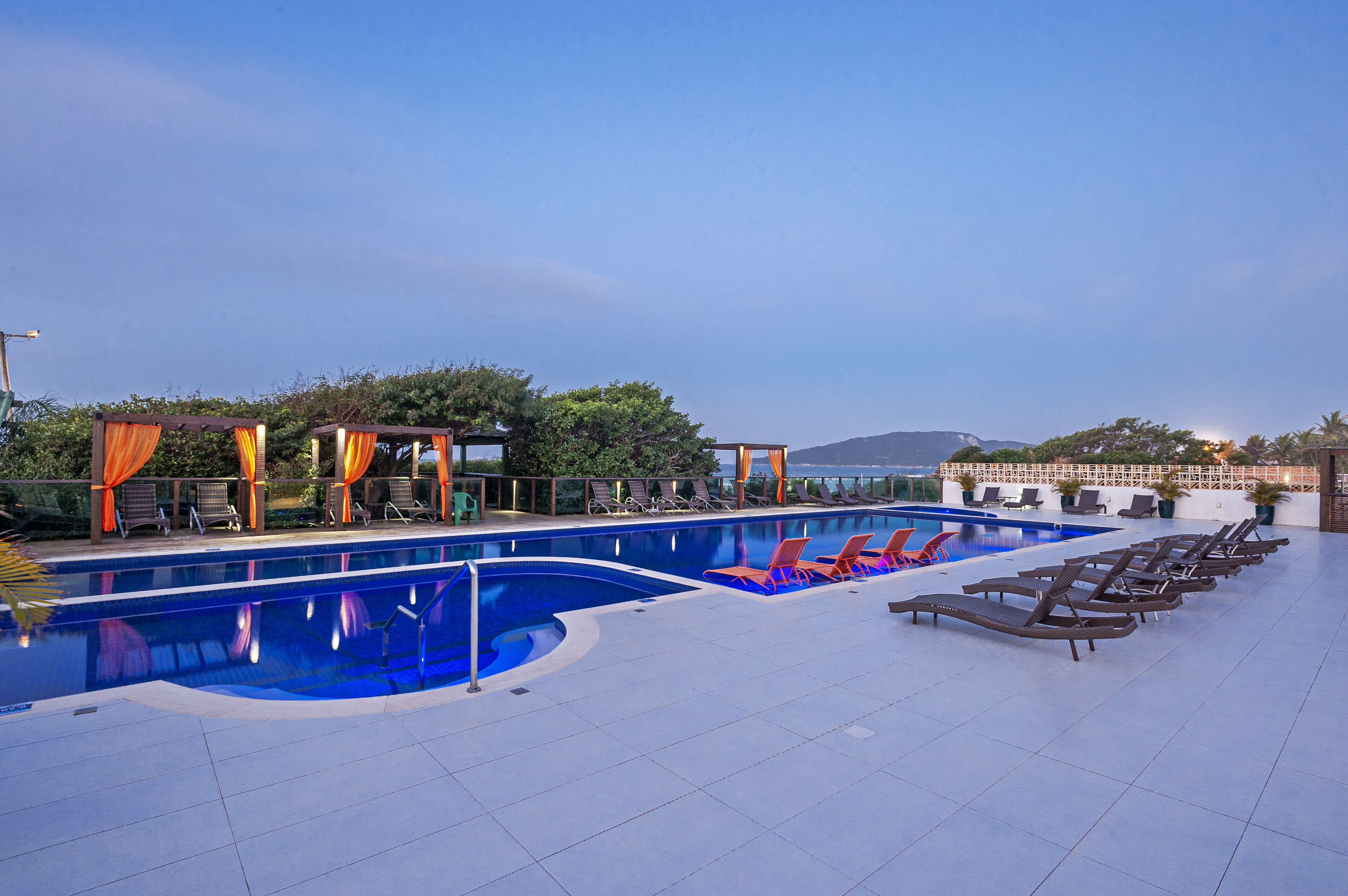 A rooftop pool with lounge chairs and a view of the sea.