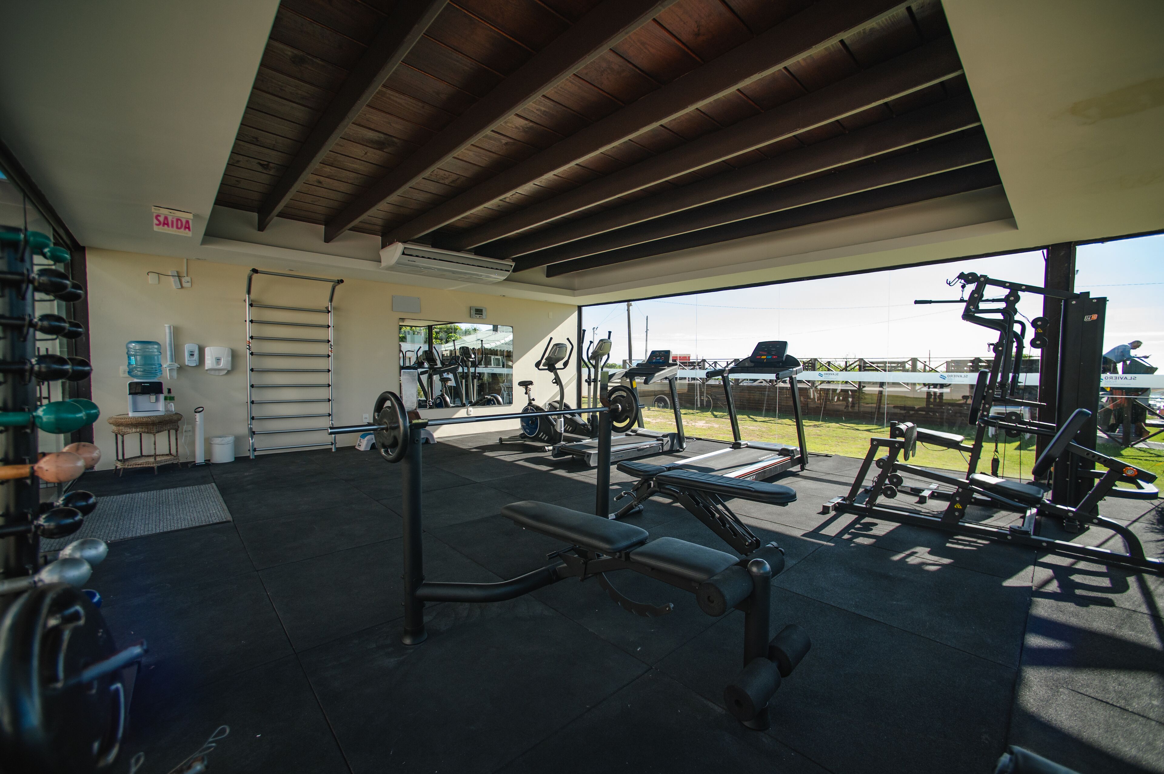 A gym with various exercise equipment, a water dispenser, and a towel rack.