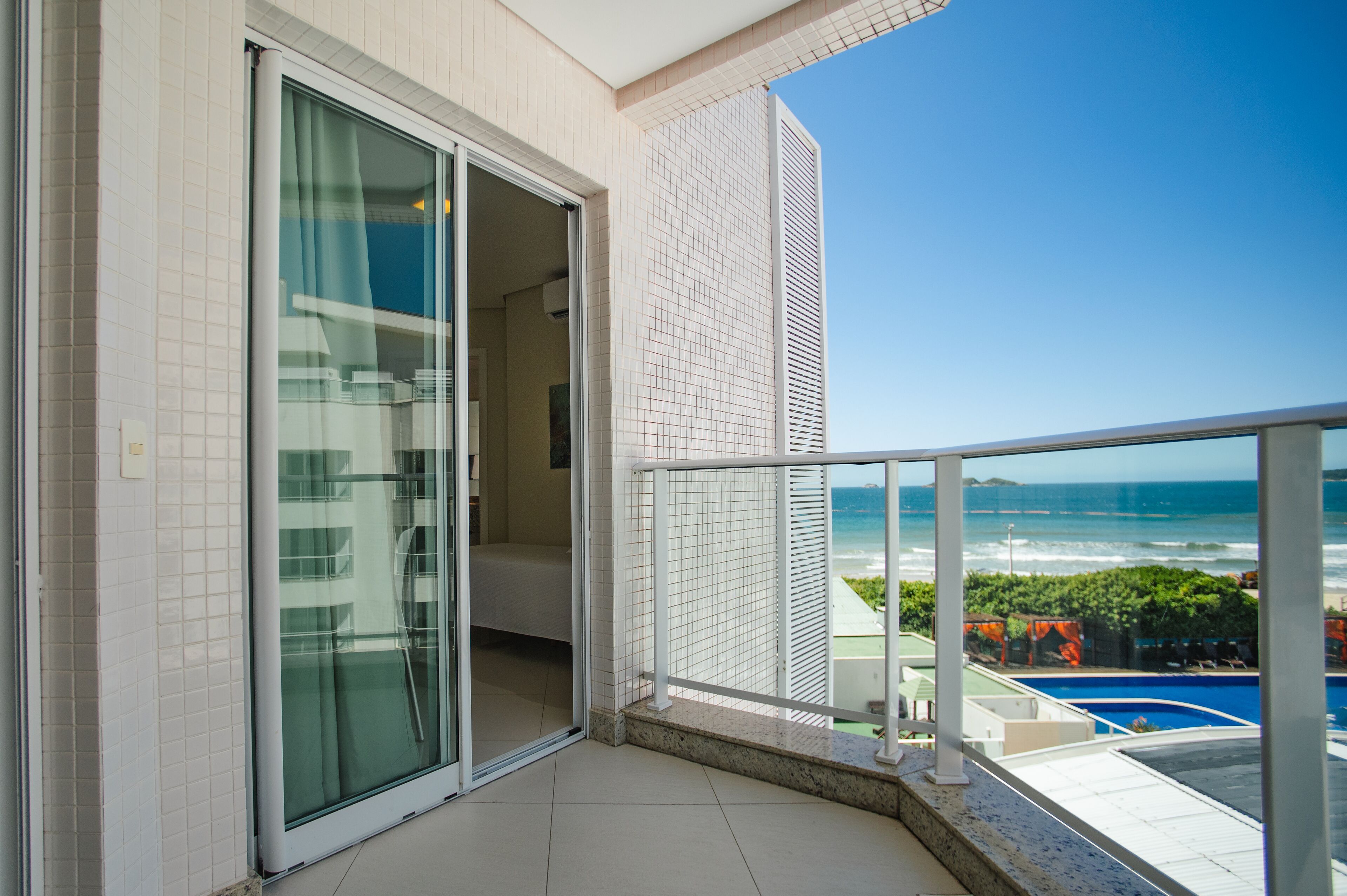 A balcony with a view of the ocean and a swimming pool.
