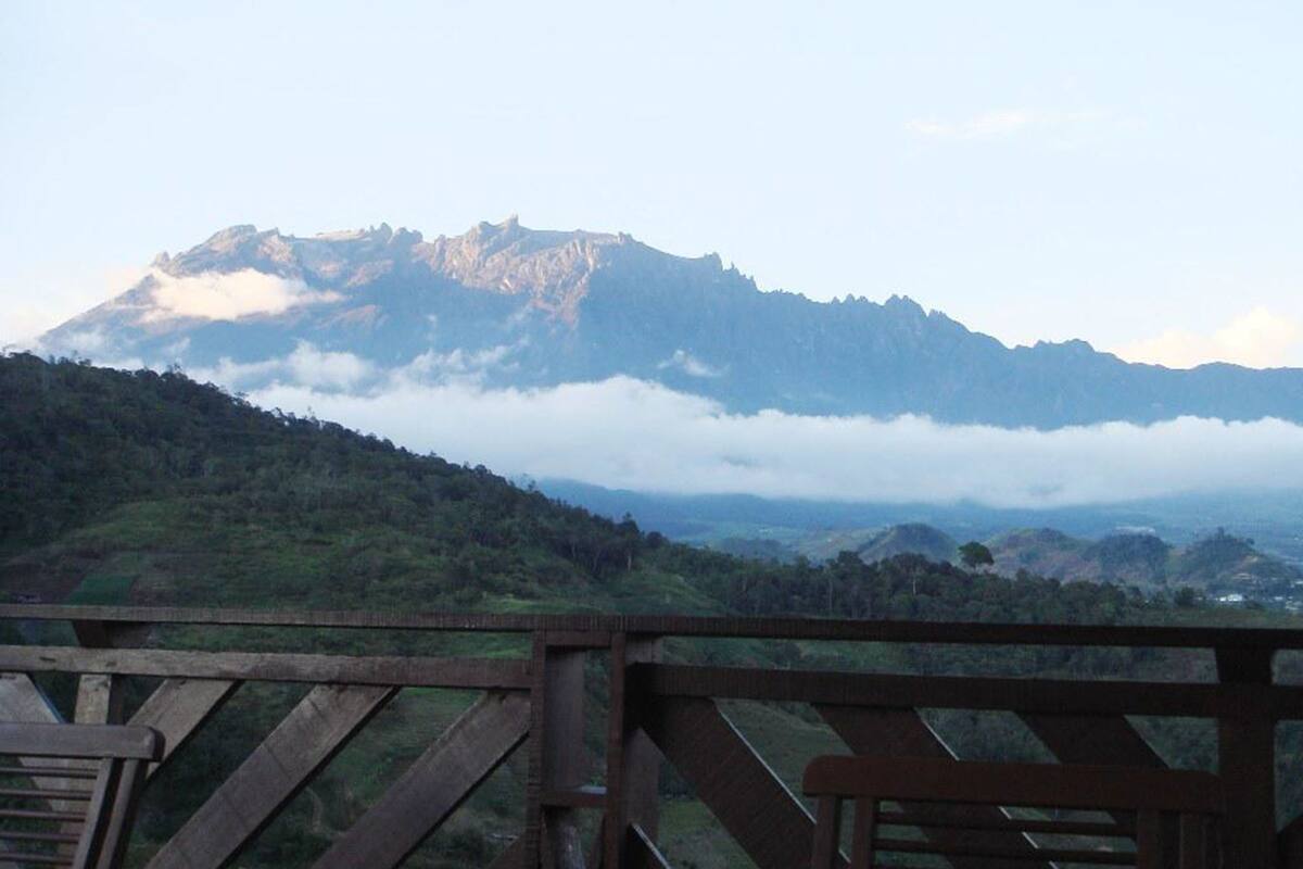 A mountain landscape with a wooden railing in the foreground.