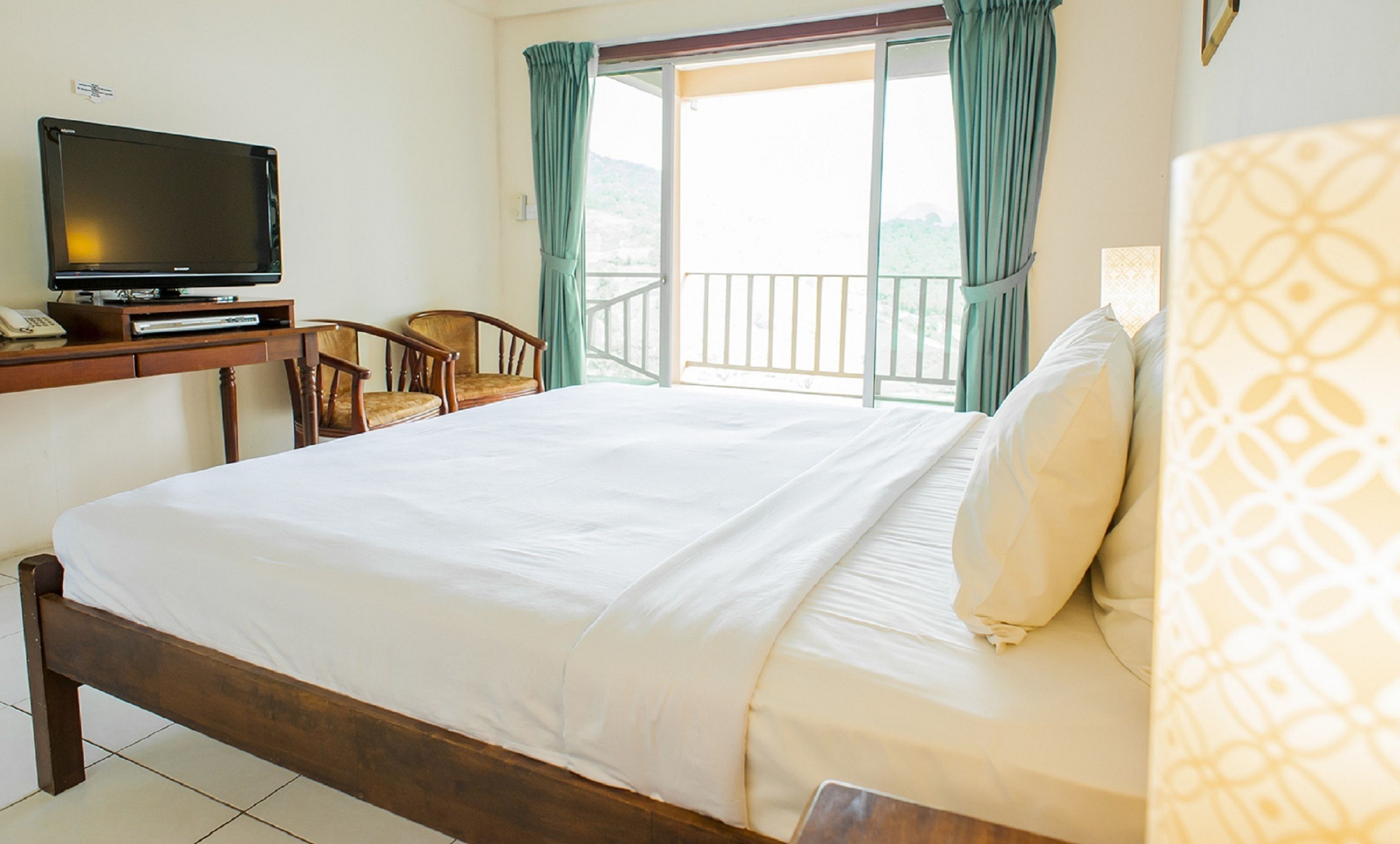Ein Hotelzimmer mit einem Bett, einem Schreibtisch mit Fernseher und einem Sessel.