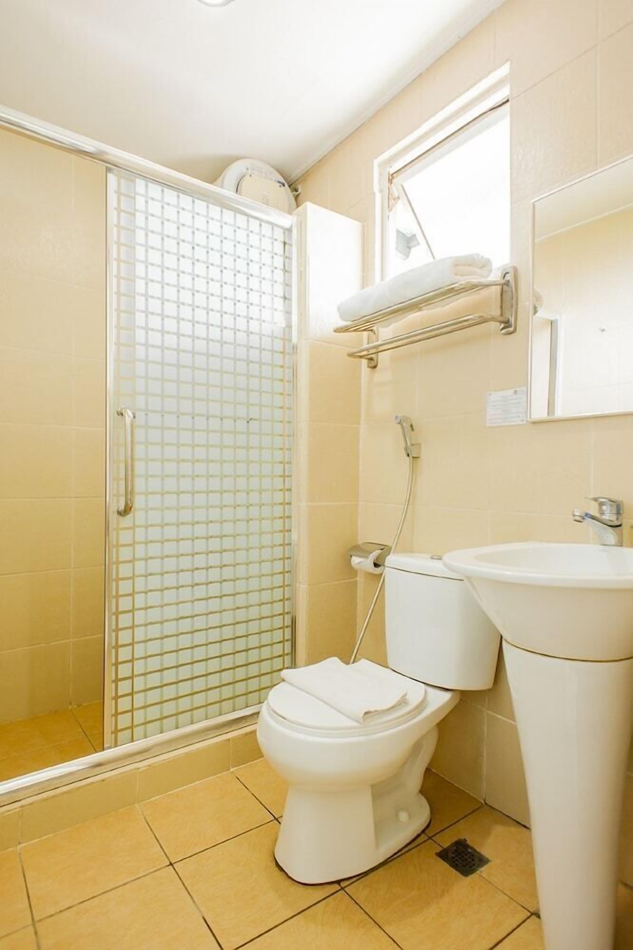 A bathroom with a toilet, sink, and glass shower enclosure.
