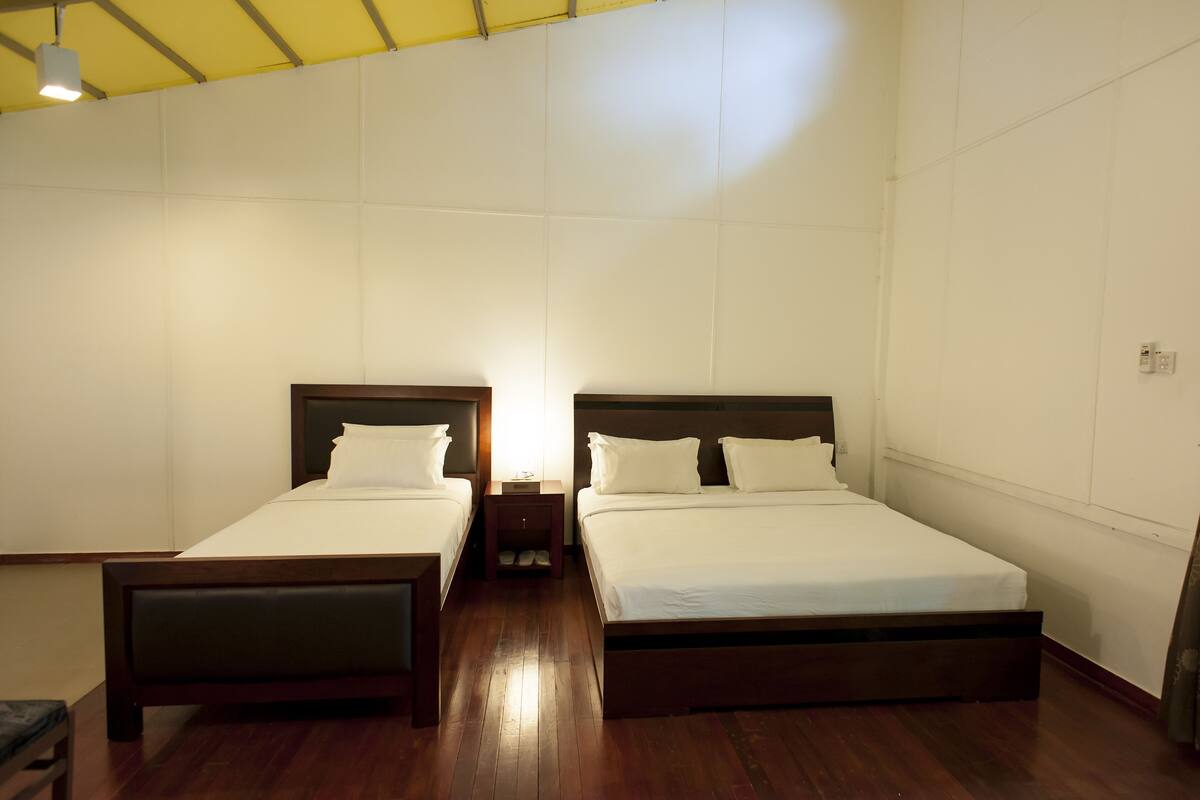 A room with two single beds, wooden headboards, and a small table between them.