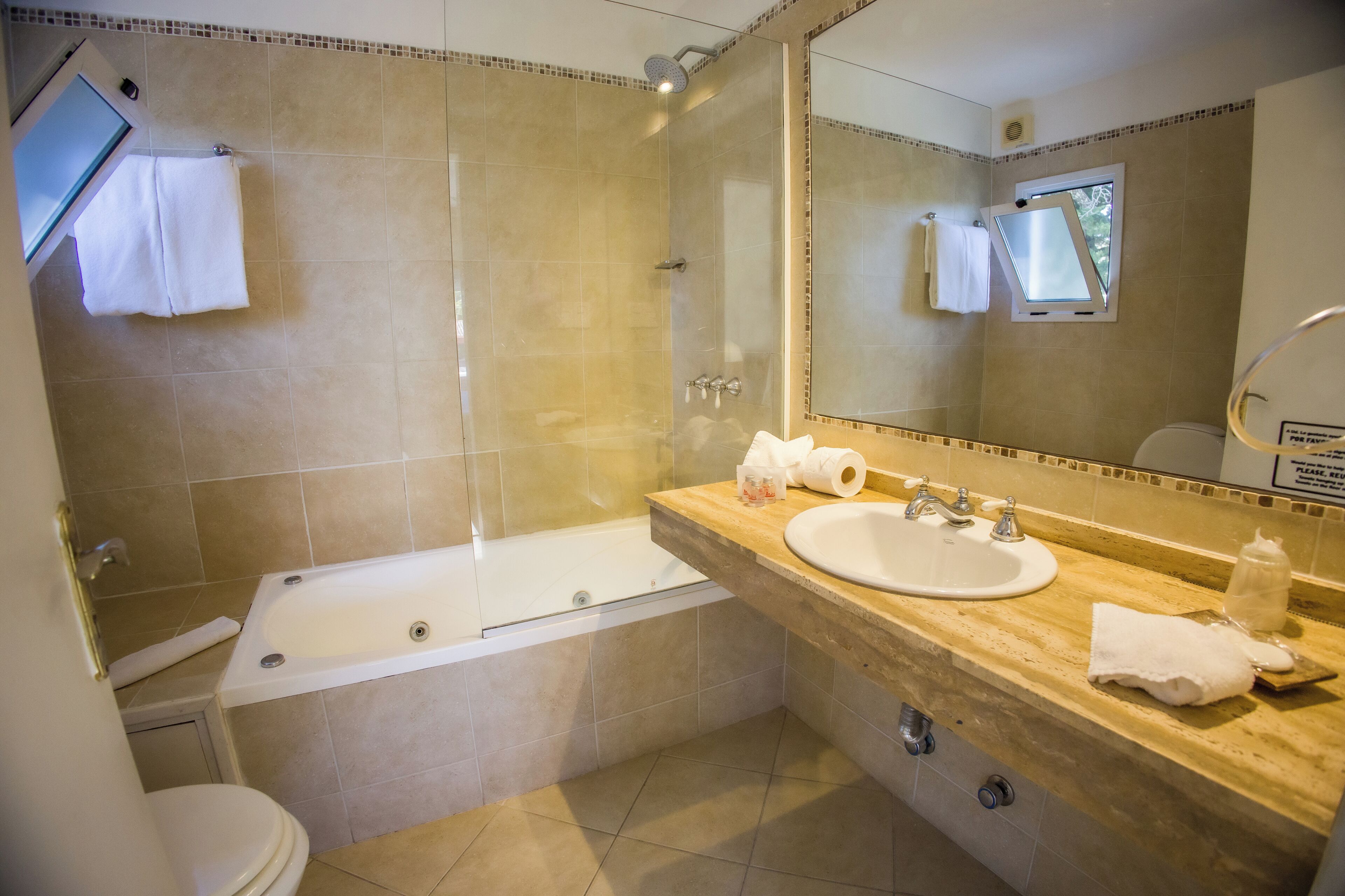 A bathroom with a bathtub, toilet, sink, and a large mirror.