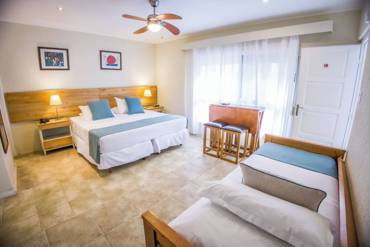 Una habitación de hotel con dos camas, un escritorio y un ventilador de techo.