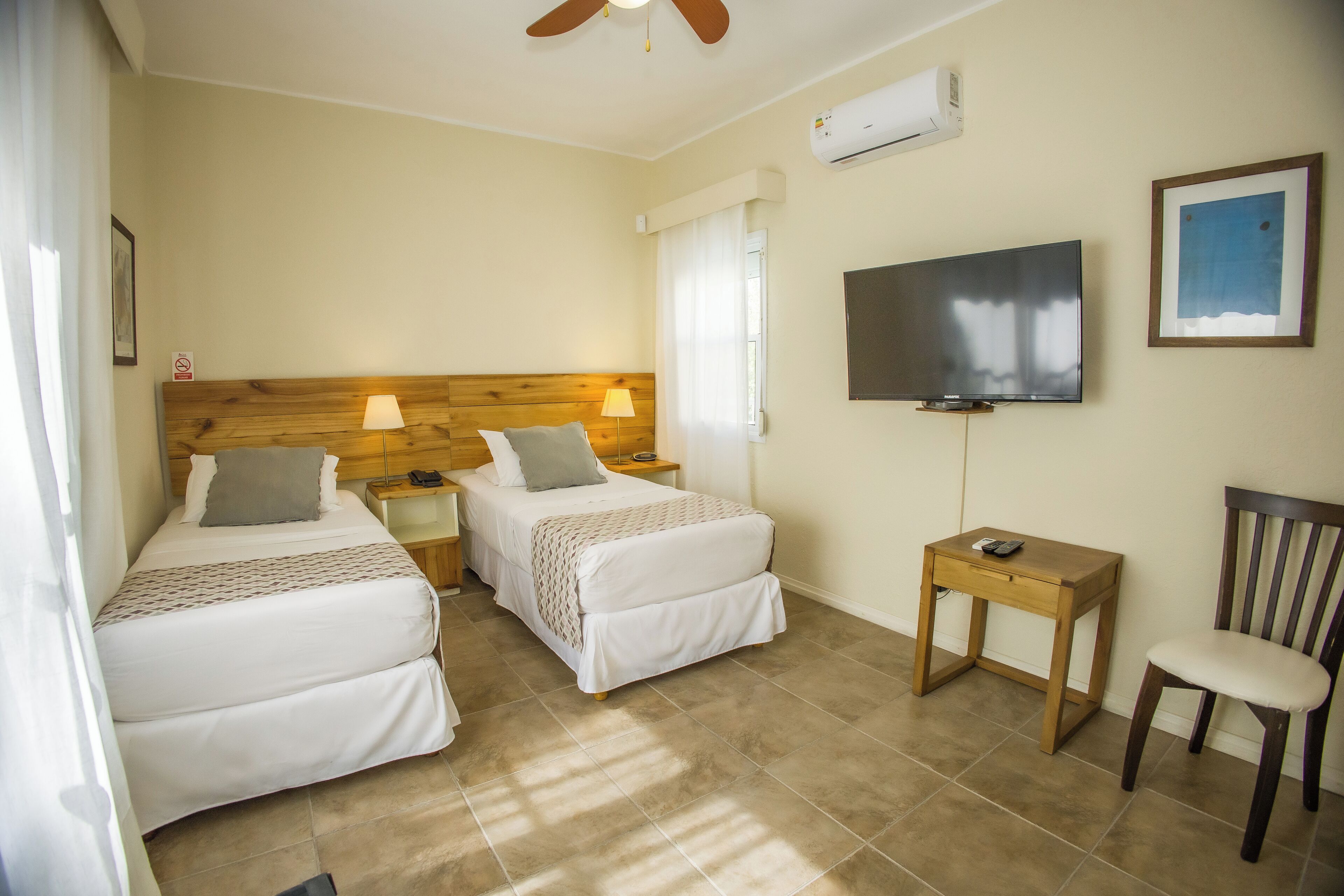 Une chambre d’hôtel avec deux lits, une télévision, une chaise et une petite table.
