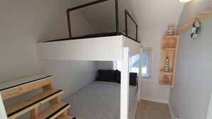 A bunk bed with a wooden ladder, a small bedside table, and a shelf with decorative items. - Plovers Cove Cottage (Wasaga Beach)