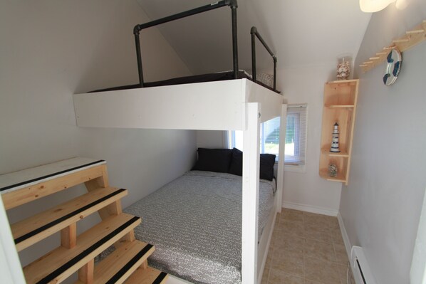 A bunk bed with a wooden ladder, a small bedside table, and a shelf with decorative items.