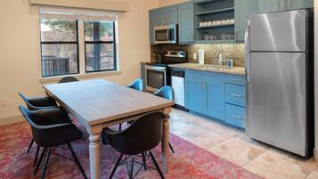 A kitchen with a dining table, chairs, a refrigerator, a microwave, an oven, and a dishwasher.