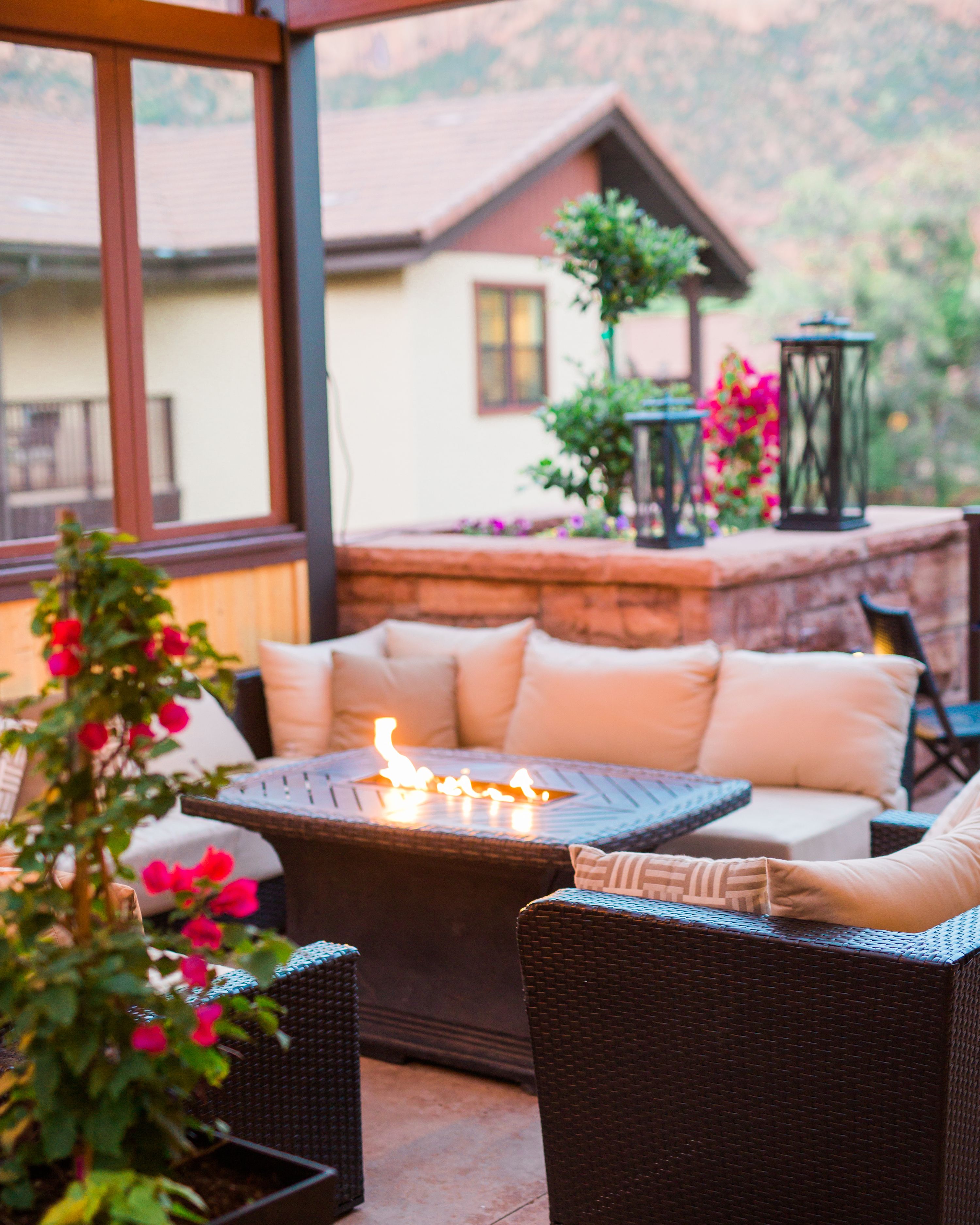 An outdoor seating area with wicker furniture, a fire pit, and a view of a mountain.