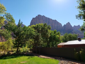 A residential area with a house, a fenced yard, and a mountain range in the background.