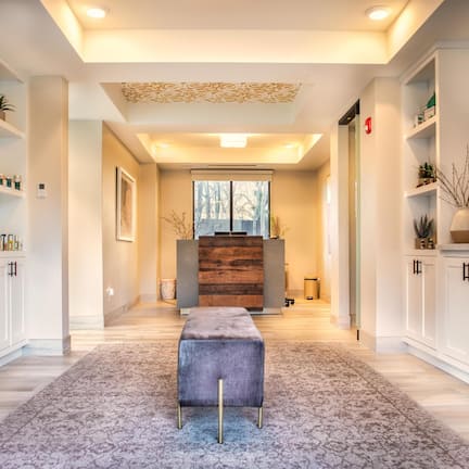 A modern hallway with white cabinetry, a central bench, and a wooden accent wall.