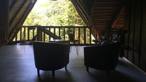 An attic room with a wooden balcony, two armchairs, and a table. - Hotel Samsara (Bahía Ballena)