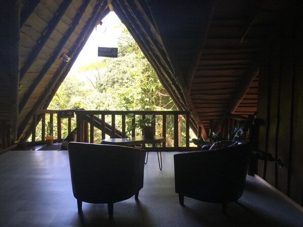 An attic room with a wooden balcony, two armchairs, and a table. - Hotel Samsara (Bahía Ballena)