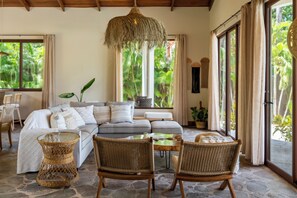 A spacious living room with a sofa, two wicker chairs, a coffee table, and a hanging light fixture. - Azul Hotel & Retreat  (Cuajiniquil)