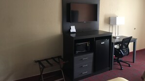 A hotel room with a desk, chair, TV, and a small cabinet. - Conner Hill Motor Lodge (Pigeon Forge)
