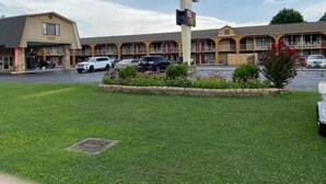 A motel with a central sign, multiple parking spaces, and a grassy area in front. - Conner Hill Motor Lodge (Pigeon Forge)