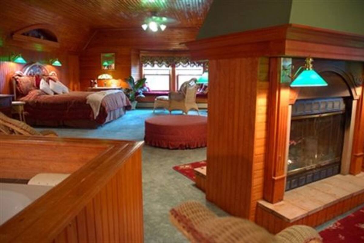A cozy room with a bed, a fireplace, and a seating area.