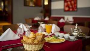 A breakfast table with croissants, a basket, a plate of eggs, and a glass of orange juice. - Atlantic Agdal (Rabat)