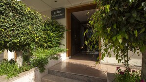 A restaurant entrance with a sign, steps leading up to it, and surrounding greenery. - Atlantic Agdal (Rabat)