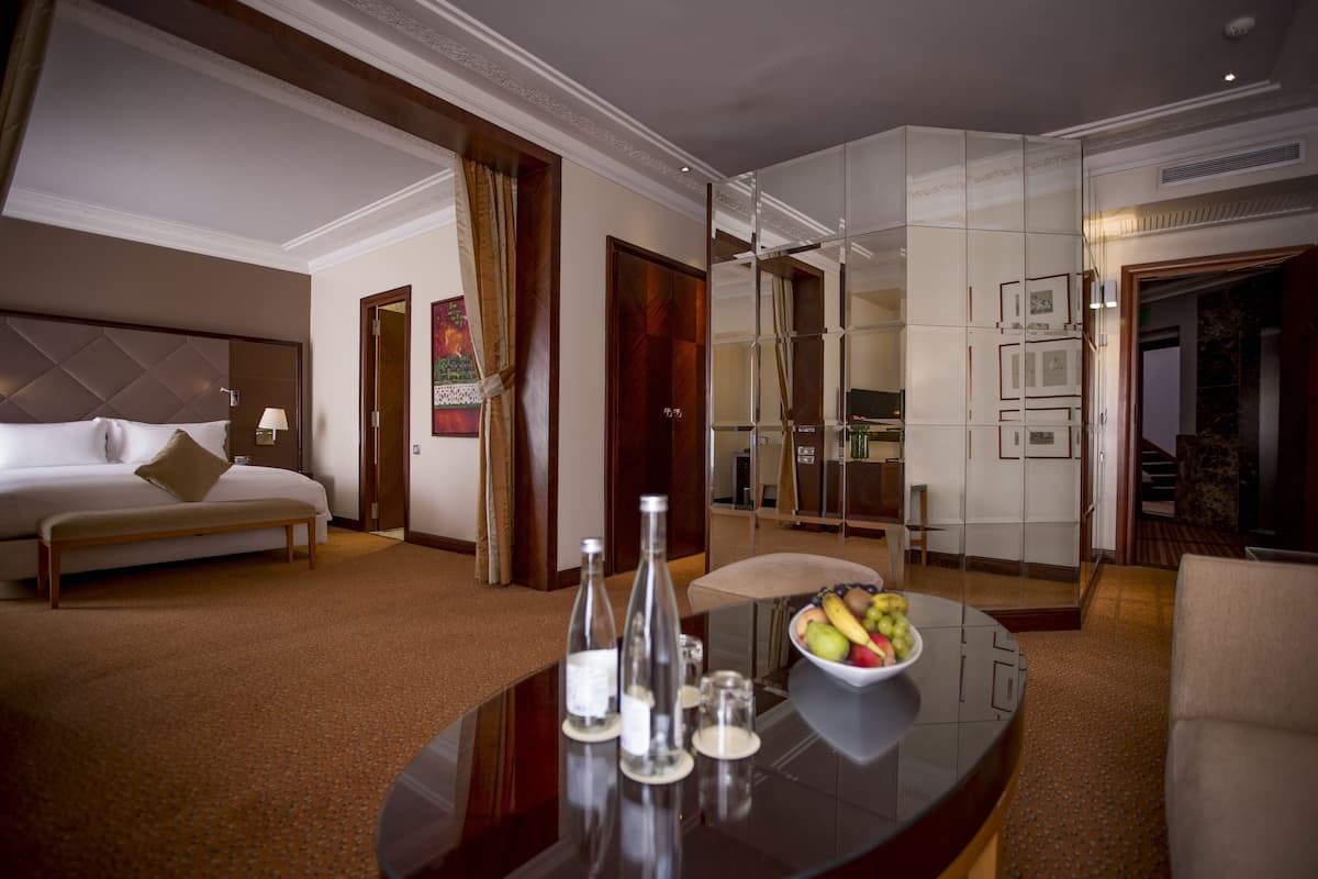 Una habitación de hotel con una cama, una mesa de comedor y un frutero, además de un espejo.