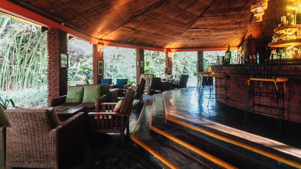 A bar area with wicker furniture and a brick wall. - Octagon Lodge (Karatu)