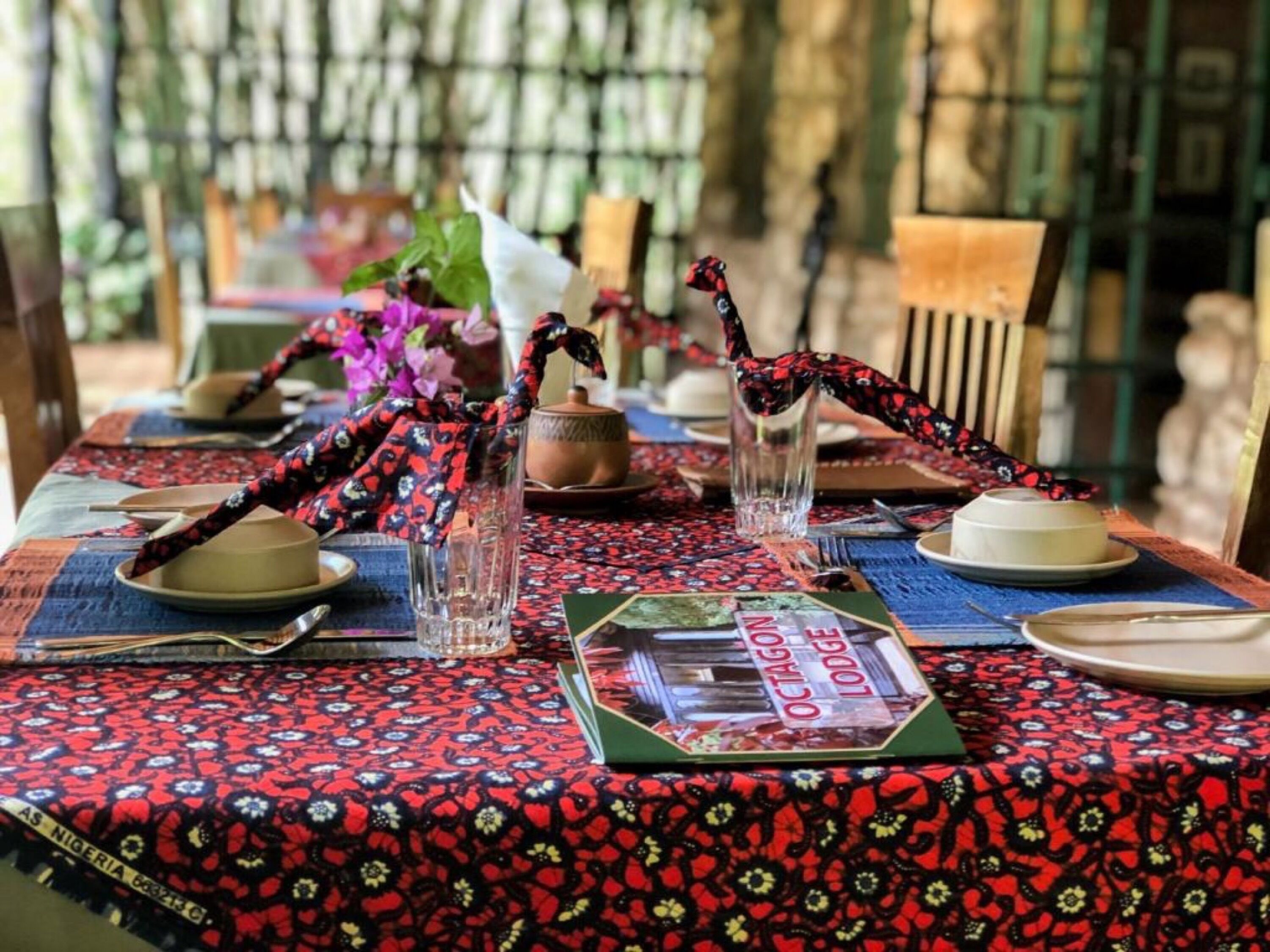 A dining table set with plates, glasses, and a menu.