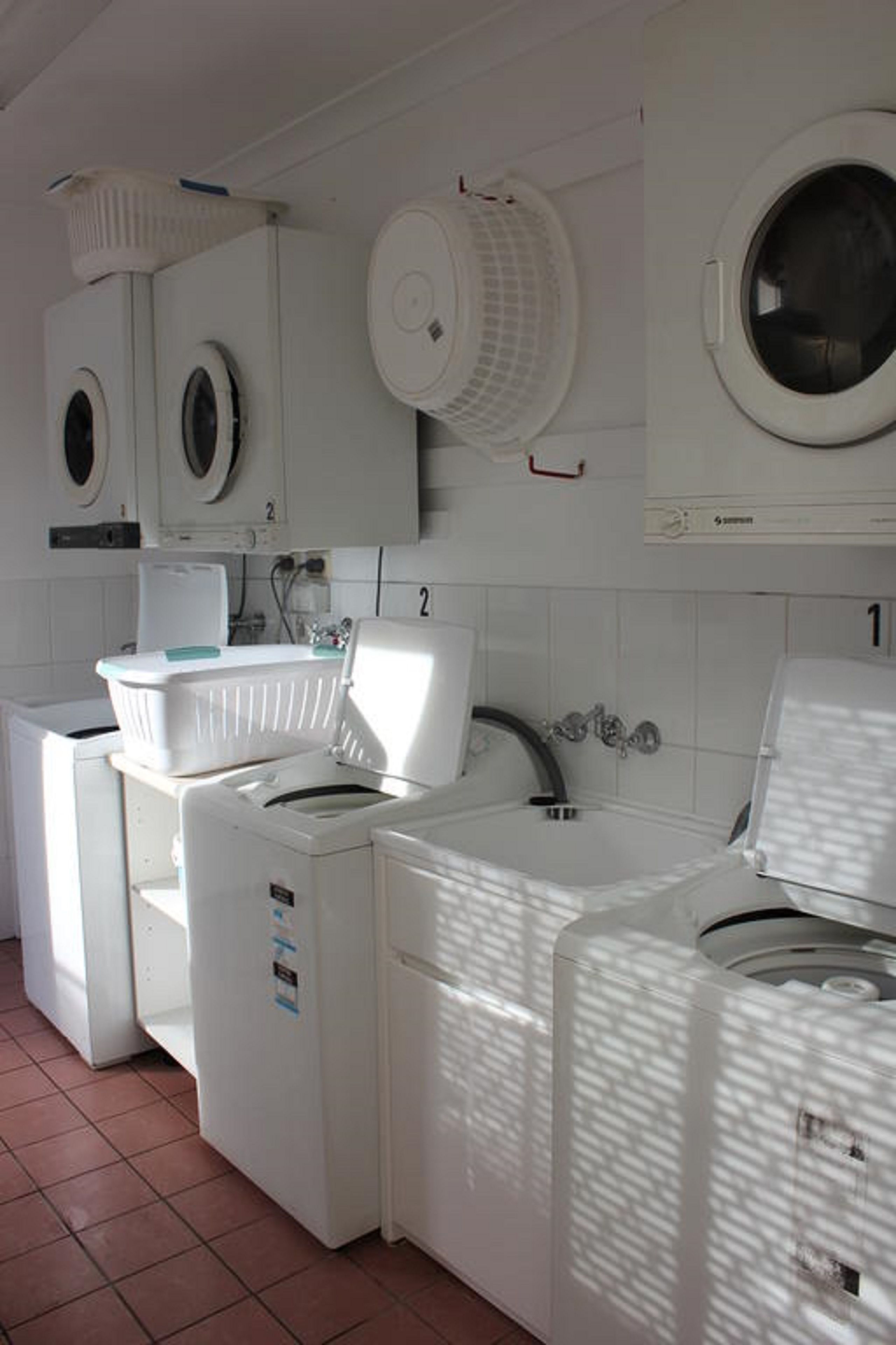 A laundry room with multiple washing machines and a sink.